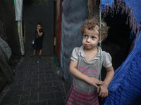 Displaced Palestinian children stand inside a United Nations school sheltering displaced people during a vaccination campaign in Deir Al-Bal...