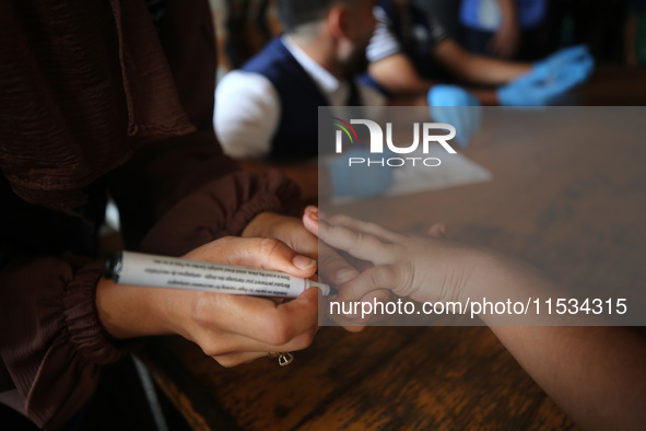 A health worker marks the finger of a Palestinian child vaccinated against polio in Deir Al-Balah in the central Gaza Strip, on September 1,...