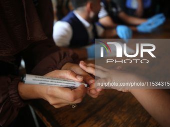 A health worker marks the finger of a Palestinian child vaccinated against polio in Deir Al-Balah in the central Gaza Strip, on September 1,...