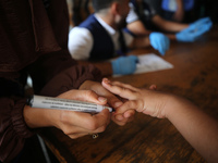 A health worker marks the finger of a Palestinian child vaccinated against polio in Deir Al-Balah in the central Gaza Strip, on September 1,...