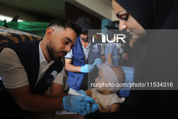 A health worker marks the finger of a Palestinian child vaccinated against polio in Deir Al-Balah in the central Gaza Strip, on September 1,...