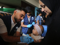 A health worker marks the finger of a Palestinian child vaccinated against polio in Deir Al-Balah in the central Gaza Strip, on September 1,...