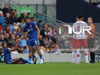 Omar Bugiel helps Alistair Smith up after a bad tackle during the Sky Bet League 2 match between AFC Wimbledon and Fleetwood Town at Plough...