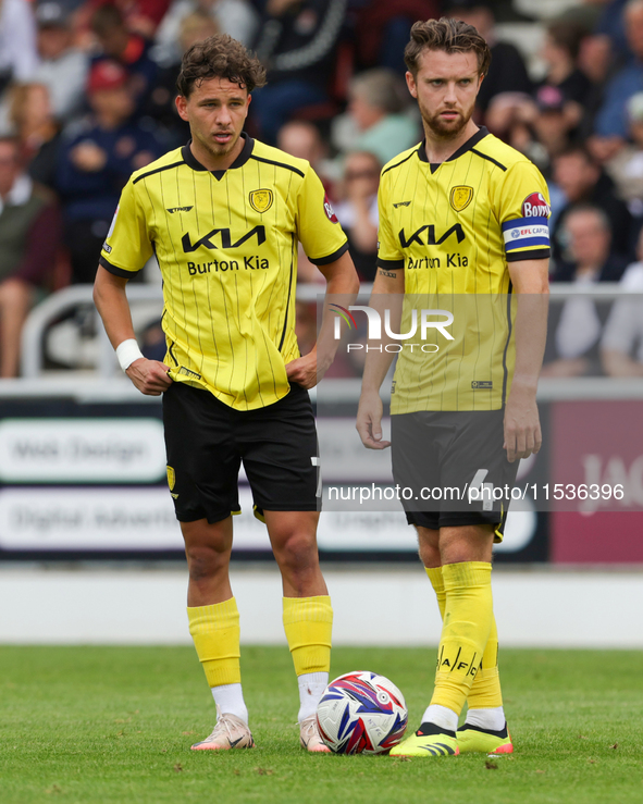 Burton Albion's Tomas Kalinauskas and Burton Albion's captain Elliot Watt stand over the ball during the first half of the Sky Bet League 1...