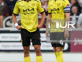 Burton Albion's Tomas Kalinauskas and Burton Albion's captain Elliot Watt stand over the ball during the first half of the Sky Bet League 1...