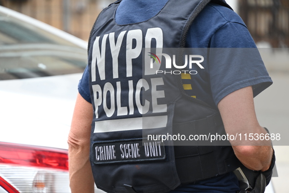 A New York City Police Department crime scene unit officer wears an NYPD crime scene unit vest at the crime scene. A 37-year-old male is sho...