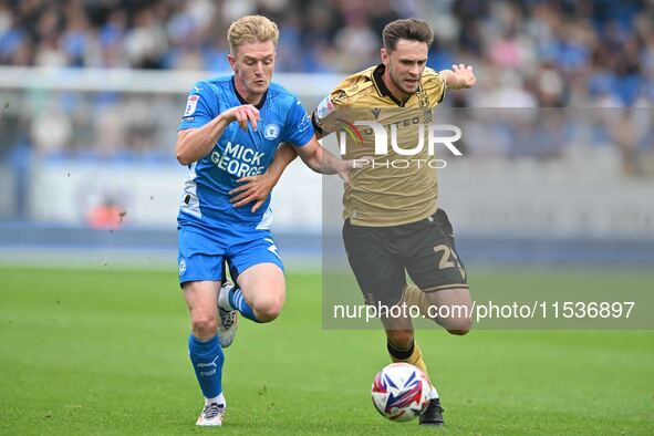 Ryan Barnett (29, Wrexham) challenges Jack Sparkes (21, Peterborough United) for the ball during the Sky Bet League 1 match between Peterbor...