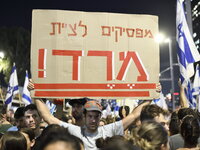 An Israeli protester carries a placard reading ''stop obeying, revolt'' as dozens of thousands of Israelis protest against the Israeli gover...