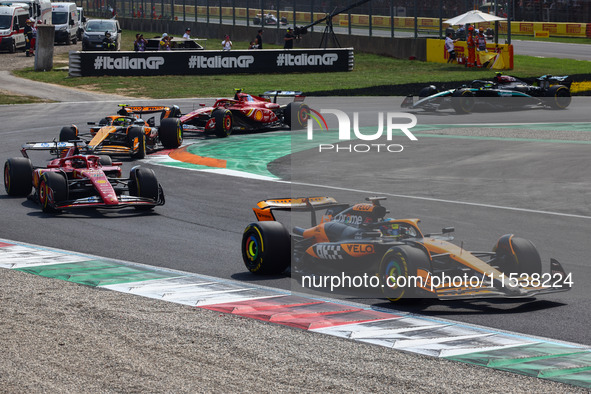 Lando Norris of McLaren, Charles Leclerc of Ferrari, Oscar Piastri of McLaren and other drivers drive after the start of the Italian Formula...