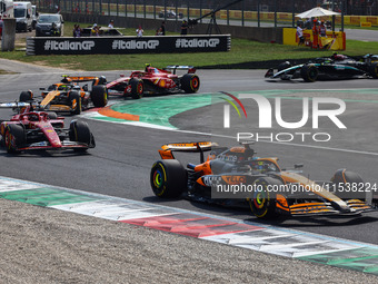 Lando Norris of McLaren, Charles Leclerc of Ferrari, Oscar Piastri of McLaren and other drivers drive after the start of the Italian Formula...