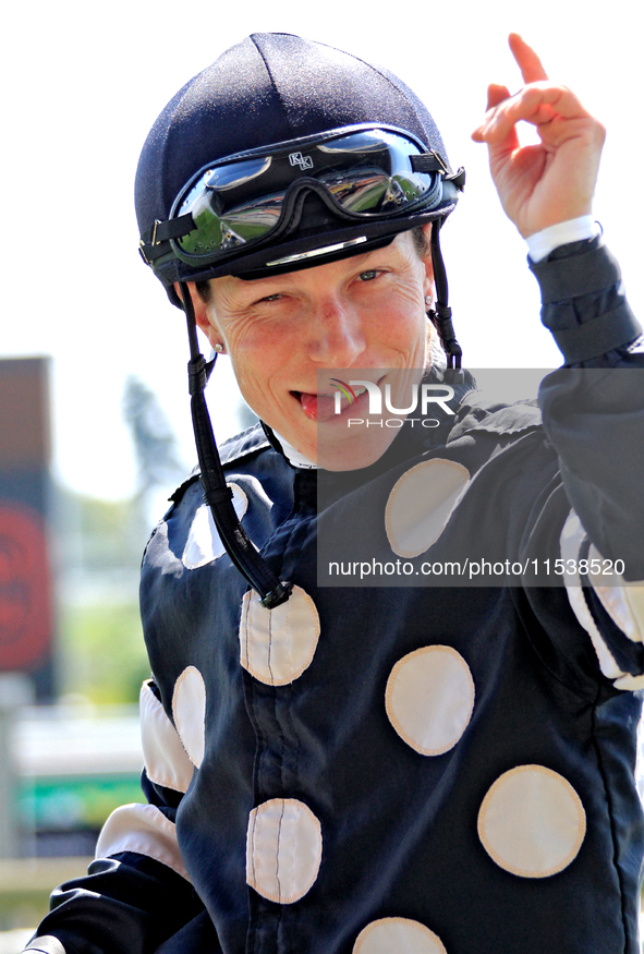 Jockey Emma-Jayne Wilson gestures to a video broadcast camera as she rides Ask in My Name to the winner's circle after a win in the second r...