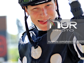 Jockey Emma-Jayne Wilson gestures to a video broadcast camera as she rides Ask in My Name to the winner's circle after a win in the second r...