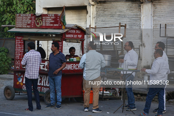 Men enjoy snacks and tea at a roadside food stall in Bazpur, Uttarakhand, India, on April 19, 2024. 