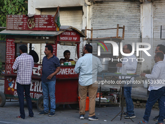 Men enjoy snacks and tea at a roadside food stall in Bazpur, Uttarakhand, India, on April 19, 2024. (