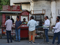 Men enjoy snacks and tea at a roadside food stall in Bazpur, Uttarakhand, India, on April 19, 2024. (