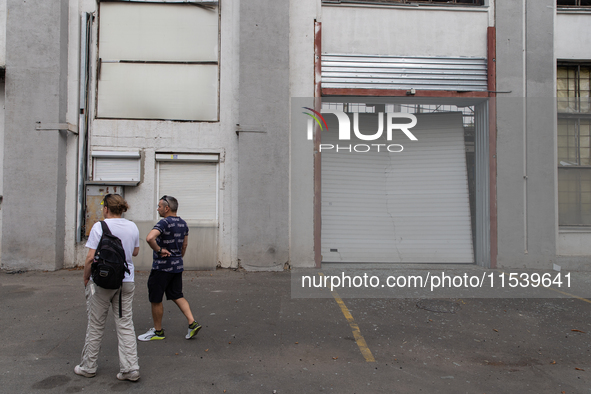 People pass warehouses damaged by a missile launched from the Russian Federation in City, Country, on September 2, 2024. 