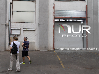 People pass warehouses damaged by a missile launched from the Russian Federation in City, Country, on September 2, 2024. (