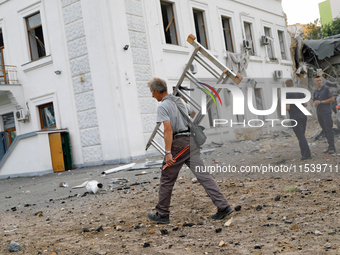 A man carries a ladder near a building on Beresteiskyi Avenue damaged by the Russian missile attack in Kyiv, Ukraine, on September 2, 2024....