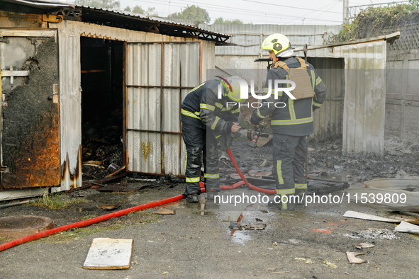 Firefighters stand at a burnt-out recycling station in the Sviatoshynskyi district damaged by the Russian missile attack in Kyiv, Ukraine, o...