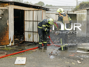 Firefighters stand at a burnt-out recycling station in the Sviatoshynskyi district damaged by the Russian missile attack in Kyiv, Ukraine, o...