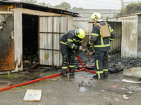 Firefighters stand at a burnt-out recycling station in the Sviatoshynskyi district damaged by the Russian missile attack in Kyiv, Ukraine, o...