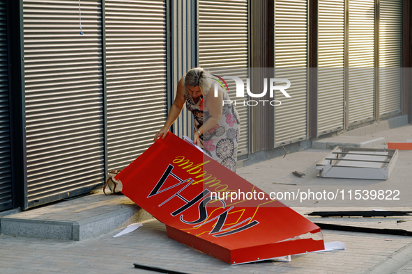 A woman picks up a signboard brought down by the Russian missile attack in the Sviatoshynskyi district of Kyiv, Ukraine, on September 2, 202...