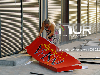 A woman picks up a signboard brought down by the Russian missile attack in the Sviatoshynskyi district of Kyiv, Ukraine, on September 2, 202...