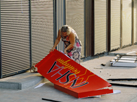 A woman picks up a signboard brought down by the Russian missile attack in the Sviatoshynskyi district of Kyiv, Ukraine, on September 2, 202...