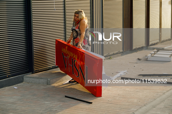 A woman picks up a signboard brought down by the Russian missile attack in the Sviatoshynskyi district of Kyiv, Ukraine, on September 2, 202...