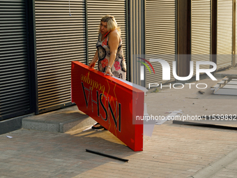 A woman picks up a signboard brought down by the Russian missile attack in the Sviatoshynskyi district of Kyiv, Ukraine, on September 2, 202...