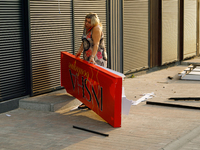 A woman picks up a signboard brought down by the Russian missile attack in the Sviatoshynskyi district of Kyiv, Ukraine, on September 2, 202...