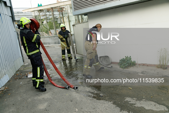 Firefighters roll hoses after putting out a fire at a recycling point in the Sviatoshynskyi district damaged by the Russian missile attack i...