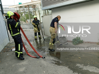 Firefighters roll hoses after putting out a fire at a recycling point in the Sviatoshynskyi district damaged by the Russian missile attack i...