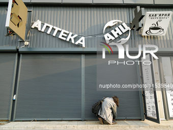 A woman lifts a security shutter at a pharmacy in the Sviatoshynskyi district after the Russian missile attack in Kyiv, Ukraine, on Septembe...