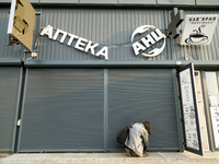 A woman lifts a security shutter at a pharmacy in the Sviatoshynskyi district after the Russian missile attack in Kyiv, Ukraine, on Septembe...