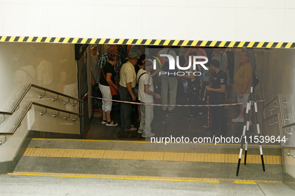 People stay at one of the entrances of the underground passage at the Sviatoshyn metro station in the Sviatoshynskyi district, closed after...