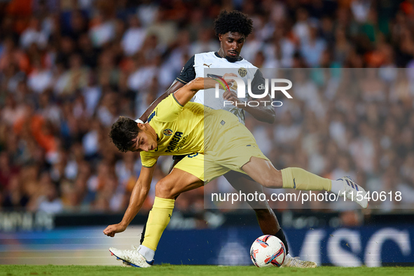 Ramon Terrats of Villarreal CF competes for the ball with Thierry Rendall of Valencia CF during the LaLiga EA Sports match between Valencia...