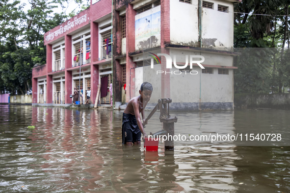 A child collects drinking water from a half-submerged tubewell in front of a shelter in Sonapur Union of Sonaimuri Upazila in Noakhali Distr...