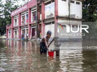 A child collects drinking water from a half-submerged tubewell in front of a shelter in Sonapur Union of Sonaimuri Upazila in Noakhali Distr...