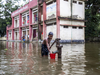 A child collects drinking water from a half-submerged tubewell in front of a shelter in Sonapur Union of Sonaimuri Upazila in Noakhali Distr...