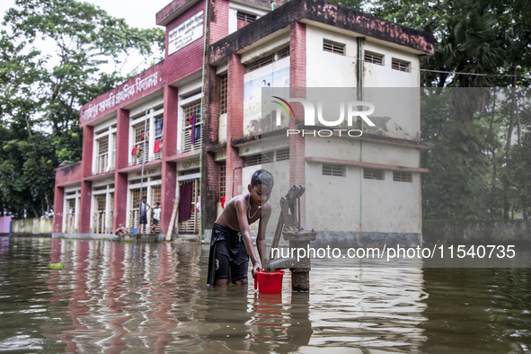 A child collects drinking water from a half-submerged tubewell in front of a shelter in Sonapur Union of Sonaimuri Upazila in Noakhali Distr...