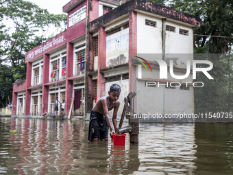 A child collects drinking water from a half-submerged tubewell in front of a shelter in Sonapur Union of Sonaimuri Upazila in Noakhali Distr...