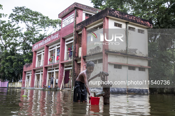 A child collects drinking water from a half-submerged tubewell in front of a shelter in Sonapur Union of Sonaimuri Upazila in Noakhali Distr...