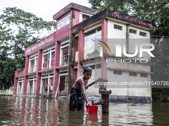 A child collects drinking water from a half-submerged tubewell in front of a shelter in Sonapur Union of Sonaimuri Upazila in Noakhali Distr...