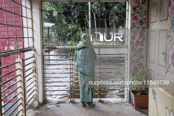 An elderly woman stands on the balcony looking out at the floodwaters of a flood shelter in Sonapur Union, Sonaimuri Upazila, Noakhali Distr...