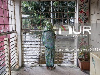 An elderly woman stands on the balcony looking out at the floodwaters of a flood shelter in Sonapur Union, Sonaimuri Upazila, Noakhali Distr...