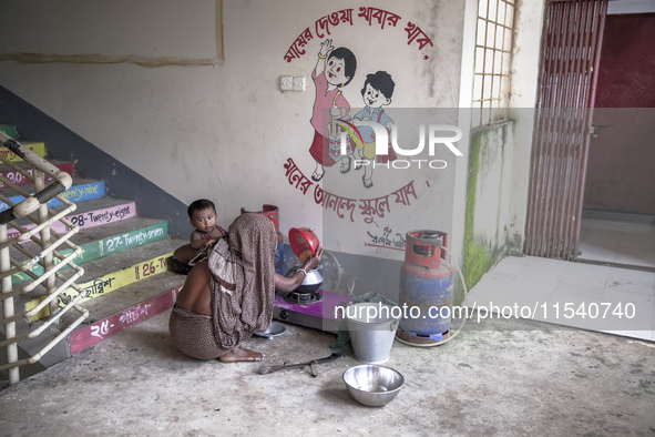 A woman cooks rice with a gas stove at a flood shelter in Sonapur Union, Sonaimuri Upazila, Noakhali District, Chittagong Division, Banglade...