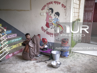 A woman cooks rice with a gas stove at a flood shelter in Sonapur Union, Sonaimuri Upazila, Noakhali District, Chittagong Division, Banglade...