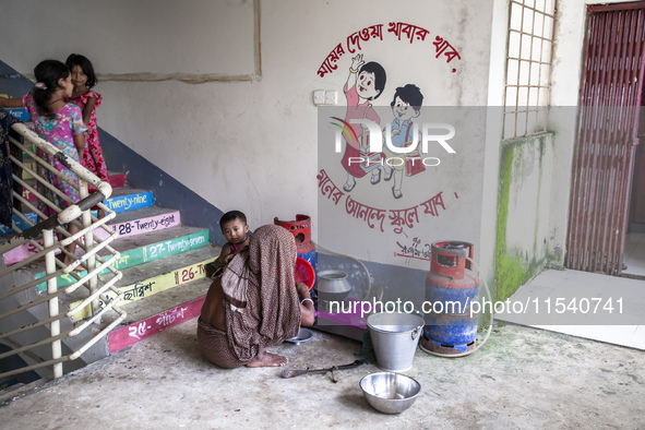 A woman cooks rice with a gas stove at a flood shelter in Sonapur Union, Sonaimuri Upazila, Noakhali District, Chittagong Division, Banglade...