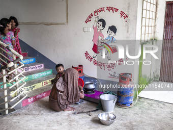 A woman cooks rice with a gas stove at a flood shelter in Sonapur Union, Sonaimuri Upazila, Noakhali District, Chittagong Division, Banglade...